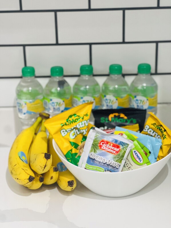 A bowl containing bananas, a bag of chips, and several bottles of water.
