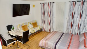 A modern bedroom with a bed, a sofa, a dining table, and chairs. - Studio Jasmin (Paris)