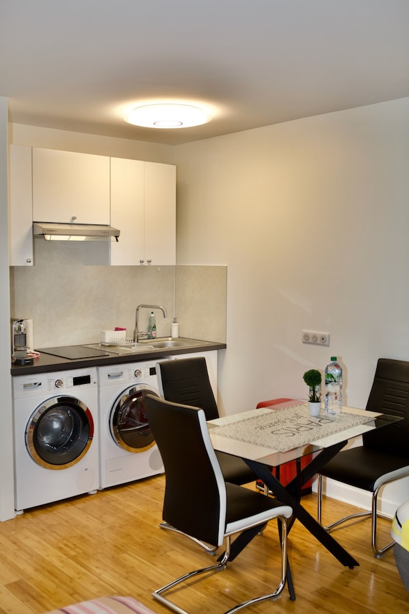A compact kitchen with a washing machine, a sink, and a table with chairs.