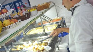 A buffet setup with various food items and a person serving. - No property  (Centro Caraguatatuba)