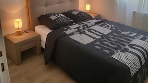A bedroom with a large bed, two bedside tables with lamps, a headboard, and two framed pictures on the wall. - Appartement Proche de Vernon Giverny (Vernon)