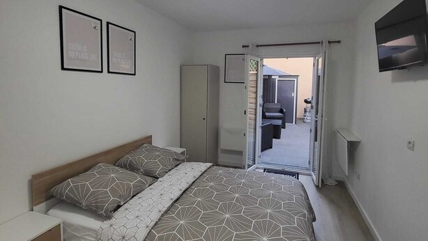 Un dormitorio con cama, mesitas de noche, armario, televisor y lámpara en el techo.