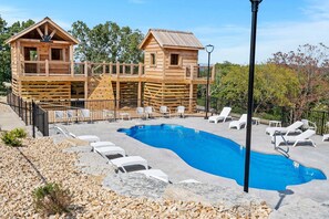 A wooden cabin with a pool, lounge chairs, and a deck.