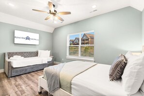 A bedroom with a bed, a sofa bed, a ceiling fan, a window with a view, and a wall-mounted sign. - Near Indoor & Outdoor Pools: Hot Tub, Game Room & Free Silver Dollar City Tickets (Kimberling City)