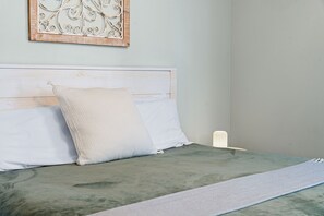 Un lit avec une tête de lit, des oreillers, une lampe de chevet et une couverture.