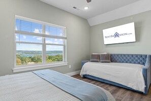 A bedroom with a large window, a bed, a TV, and a view of a landscape.