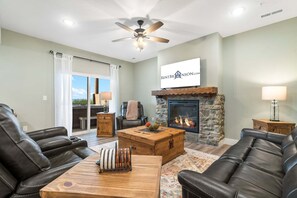 A living room with leather sofas, a fireplace, a ceiling fan, and a view through a glass door. - Near Indoor & Outdoor Pools: Hot Tub, Game Room & Free Silver Dollar City Tickets (Kimberling City)