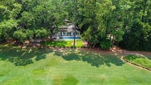 An aerial view of a large house surrounded by dense trees, with a well-maintained lawn and a swimming pool. - Luxury Sea Pines Sanctuary • Pool • Spa • Peaceful Lawn• Golf View (Hilton Head Island)