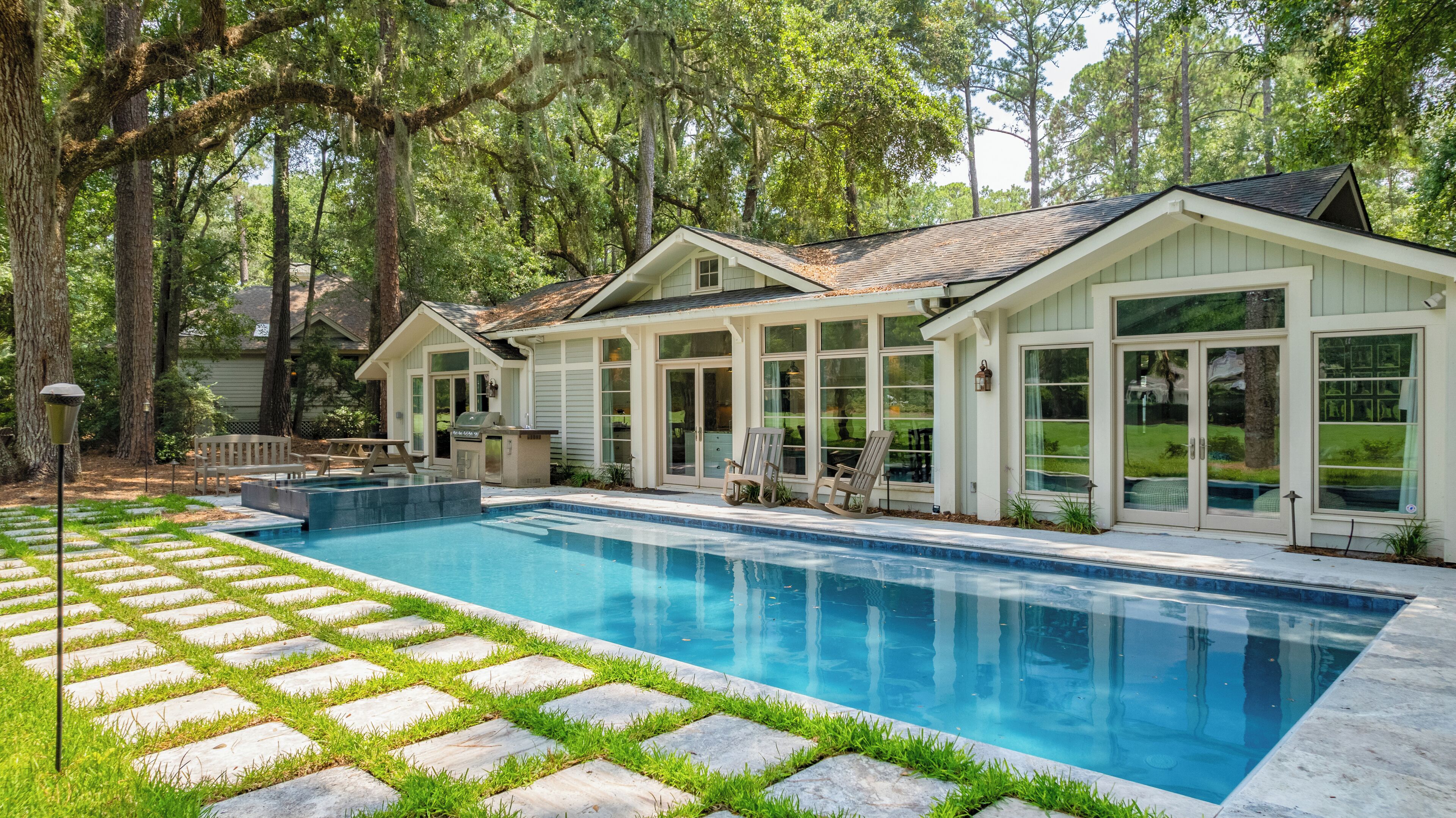 A residential property with a swimming pool, a covered patio, and a large deck area.