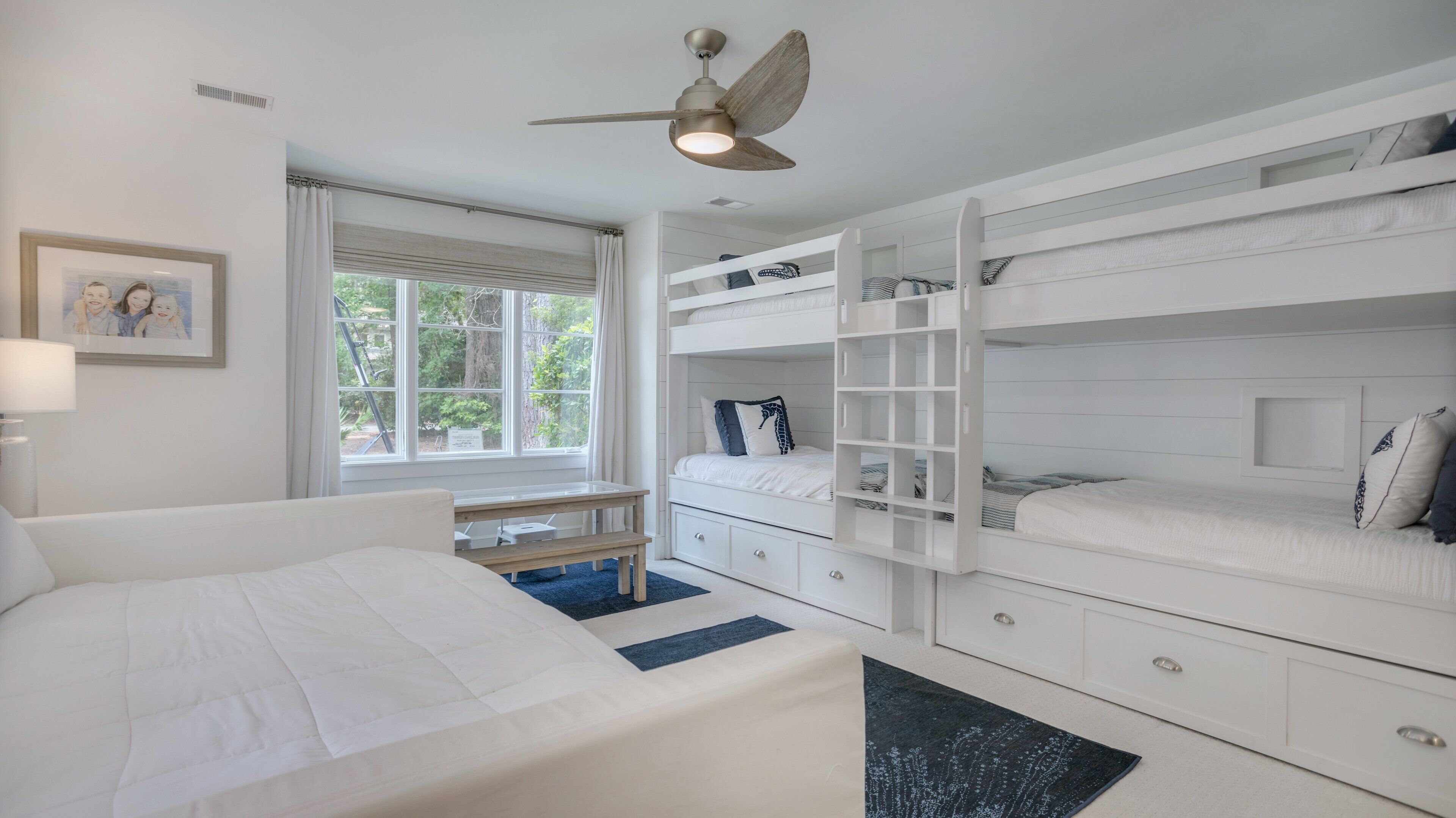 A bedroom with a bunk bed, a desk, and a window with curtains.