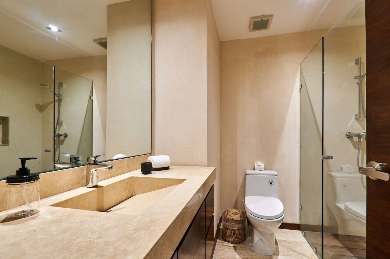 Une salle de bain moderne dotée d’un meuble-lavabo à deux vasques, de toilettes et d’une douche à parois de verre.