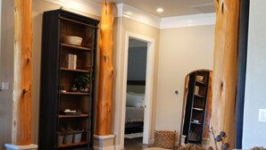 A room with wooden columns, a bookshelf, and a table with decorative flowers. - TuscanyNTexas (La Grange)