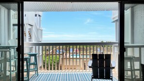 Een balkon met uitzicht op een zwembad en een houten terras.
