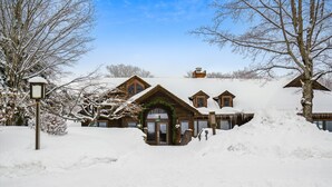 A snow-covered lodge with a prominent entrance and a large snow pile in front.