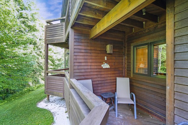 A wooden cabin with a porch, a small table, and a bench.