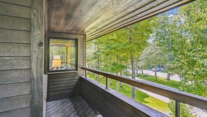 Un balcon en bois donnant sur un parc et une route.