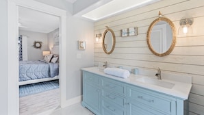 Une salle de bain avec un meuble-lavabo, deux miroirs et un espace douche.