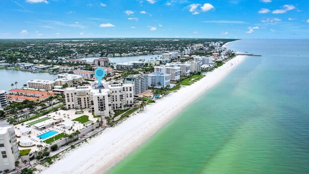 A coastal hotel with a long beachfront, multiple buildings, and a marina. - Beachfront delight in the Moorings! (Naples)