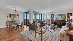 A spacious living room with a dining area, large windows, and a television. - Beachfront delight in the Moorings! (Naples)