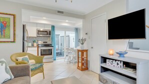 Ein modernes Wohnzimmer mit Flachbildfernseher, Essbereich und einer Küche mit Mikrowelle und Backofen.