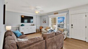Ein Wohnzimmer mit braunem Sofa, einem weißen Schrank, einem Flachbildfernseher und einem Deckenventilator.