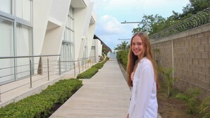 A modern building with a straight pathway, a metal railing, and a brick wall with barbed wire.