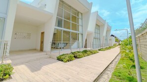 A modern building with large windows, a paved walkway, and a metal railing.