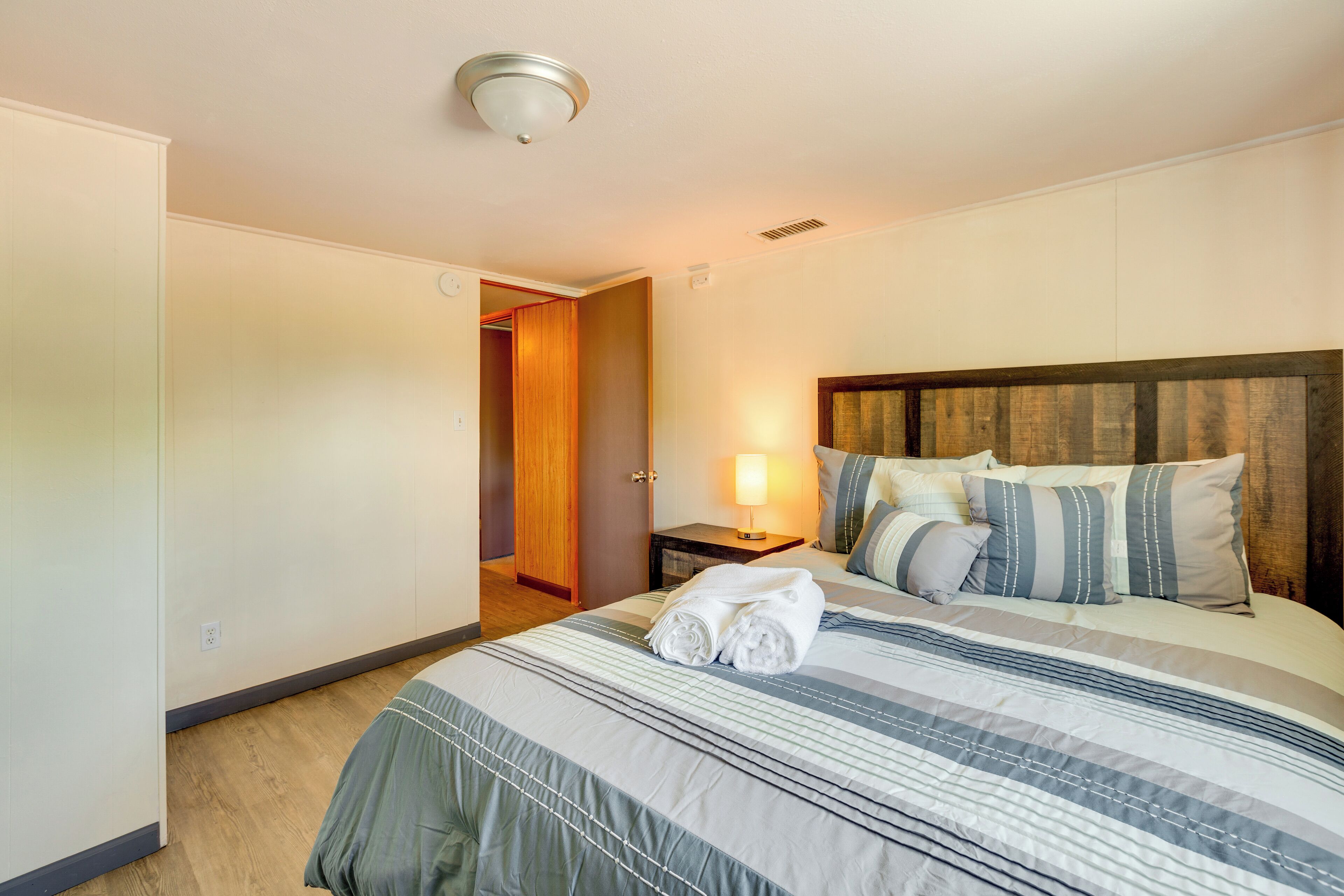 Une chambre d’hôtel avec un grand lit, une table de chevet avec une lampe et une tête de lit en bois.
