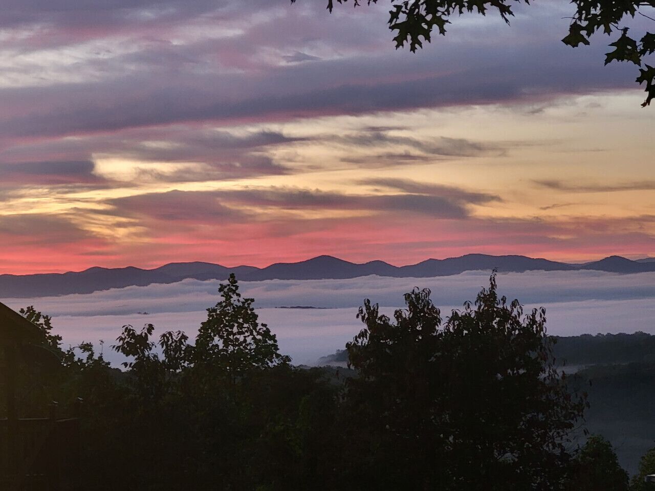 Un paysage montagneux, avec un coucher de soleil et des nuages.