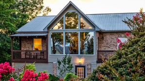A two-story house with a large central window, a balcony on the upper floor, and a small front porch. - Sky Sunset Stay: Mountain Views, Hot Tub, Gameroom (Blue Ridge)