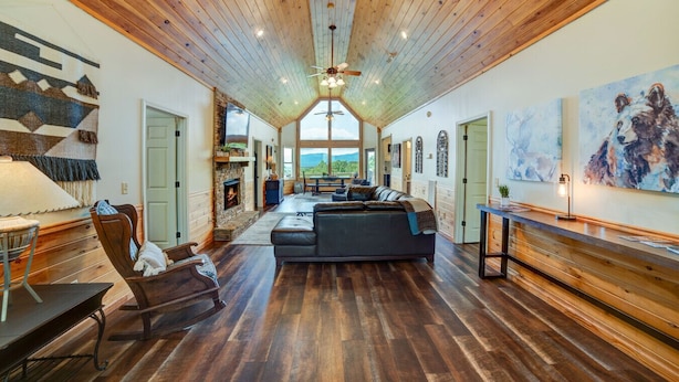 A spacious living area with a fireplace, a large couch, and a view of the outdoors. - Sky Sunset Stay: Mountain Views, Hot Tub, Gameroom (Blue Ridge)