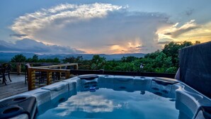 A hot tub on a wooden deck with a view of mountains and a sunset. - Sky Sunset Stay: Mountain Views, Hot Tub, Gameroom (Blue Ridge)
