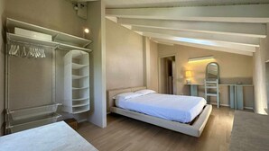 A bedroom with a bed, a desk, a chair, a wardrobe, and a mirror.