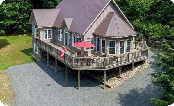 A large house with a deck, a flag, and outdoor furniture.
