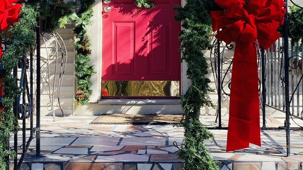 A red door with a wreath and red bows, surrounded by greenery and red bows. - Cozy Cottage in the country,  Pet Friendly. 2.8 mil from Tupelo Furniture Market (Tupelo)