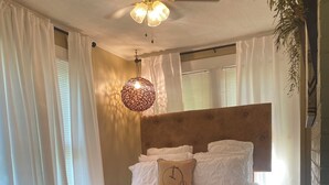 A bedroom with a bed, white curtains, a ceiling fan, and a hanging light fixture. - Cozy Cottage in the country,  Pet Friendly. 2.8 mil from Tupelo Furniture Market (Tupelo)