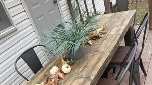 A wooden deck with a dining table and chairs, a potted plant, and decorative pumpkins. - Cozy Cottage in the country,  Pet Friendly. 2.8 mil from Tupelo Furniture Market (Tupelo)