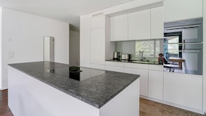 A modern kitchen with white cabinetry, a granite countertop, and stainless steel appliances. - Chic Wollishofen 1BR w/ Storage & W/D, nr Local Market, by Blueground (Zurich)