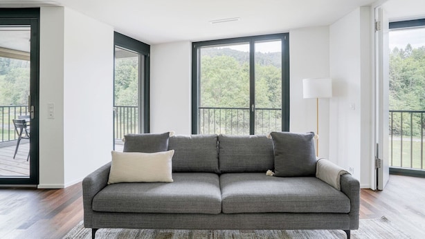 A modern living room with a grey sofa, two windows, and a balcony. - Chic Wollishofen 1BR w/ Storage & W/D, nr Local Market, by Blueground (Zurich)
