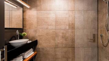 Un baño moderno con un lavabo grande, espejo y ducha.