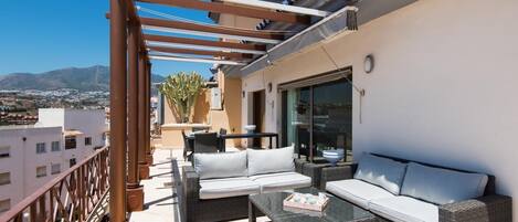 Un balcón con mobiliario exterior, una pérgola y vistas a la ciudad y a las montañas.