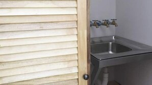 A bathroom with a wooden door, a stainless steel sink, and two faucets.