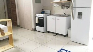 A compact kitchen with white cabinets, a stove, a sink, and a refrigerator.