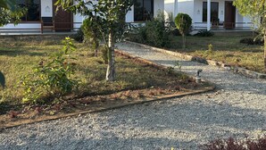 A building with a green roof and white walls, surrounded by gravel paths and greenery. - Tiger Wildlife Resort (Jagatpur)