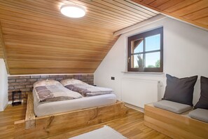 A loft-style bedroom with a sloped ceiling, a wooden bed frame, a built-in bench, and a window providing natural light. - Holiday Home 'Die Bahnstation' with Private Terrace, Private Garden and Wi-Fi (Friedrichshafen)