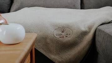 Ein graues Sofa mit einer Decke, die ein Logo und Text zeigen.