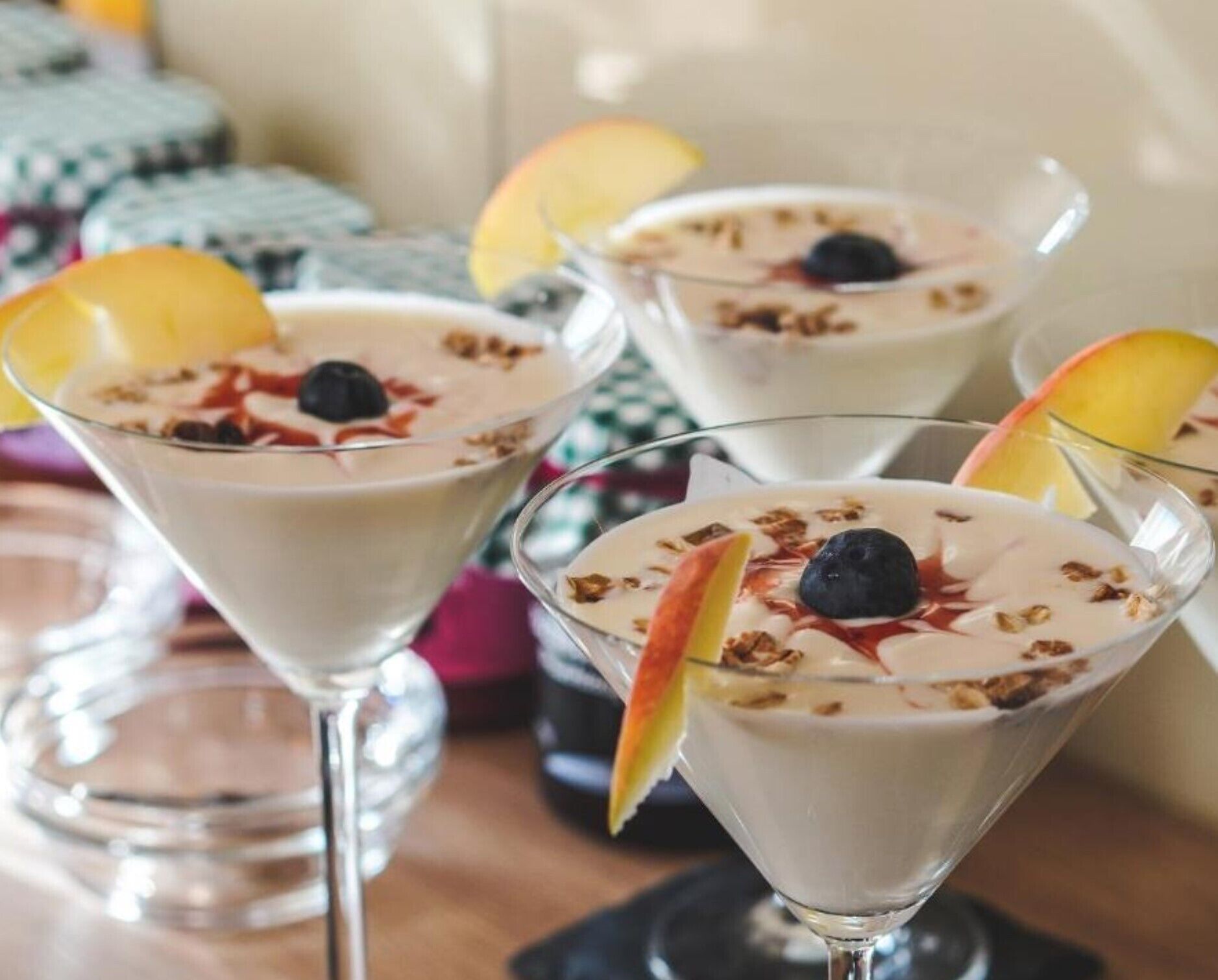 Three dessert drinks in martini glasses with fruit garnishes.