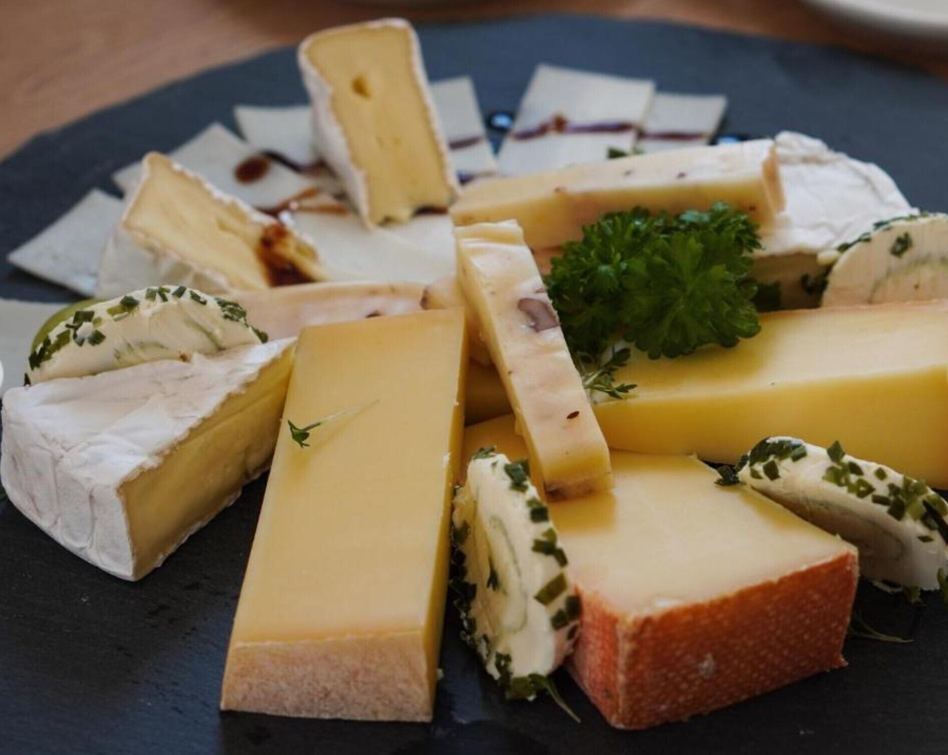 A variety of cheeses arranged on a slate board.