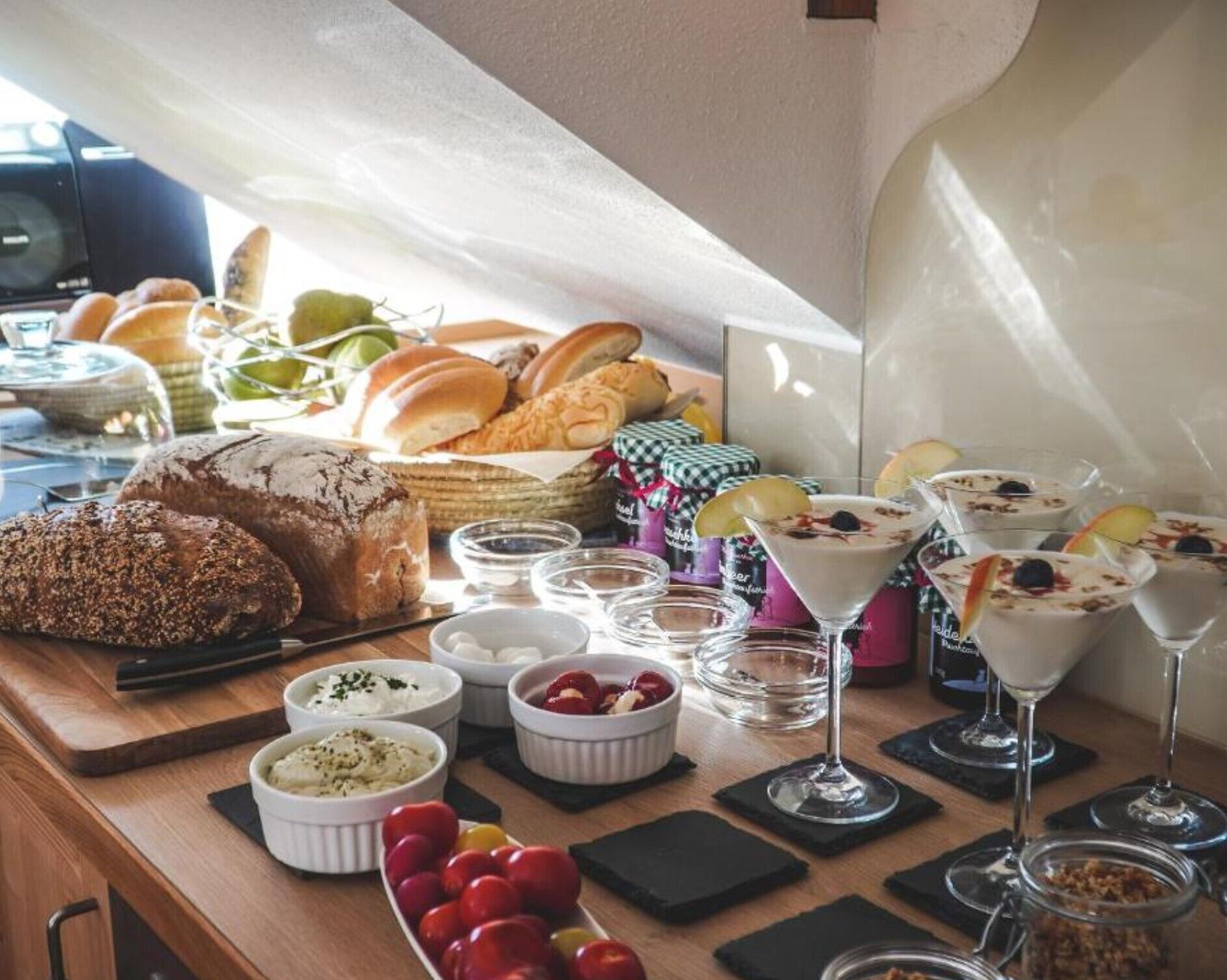 A buffet table with various breads, pastries, and desserts, along with small bowls of dips and garnishes.