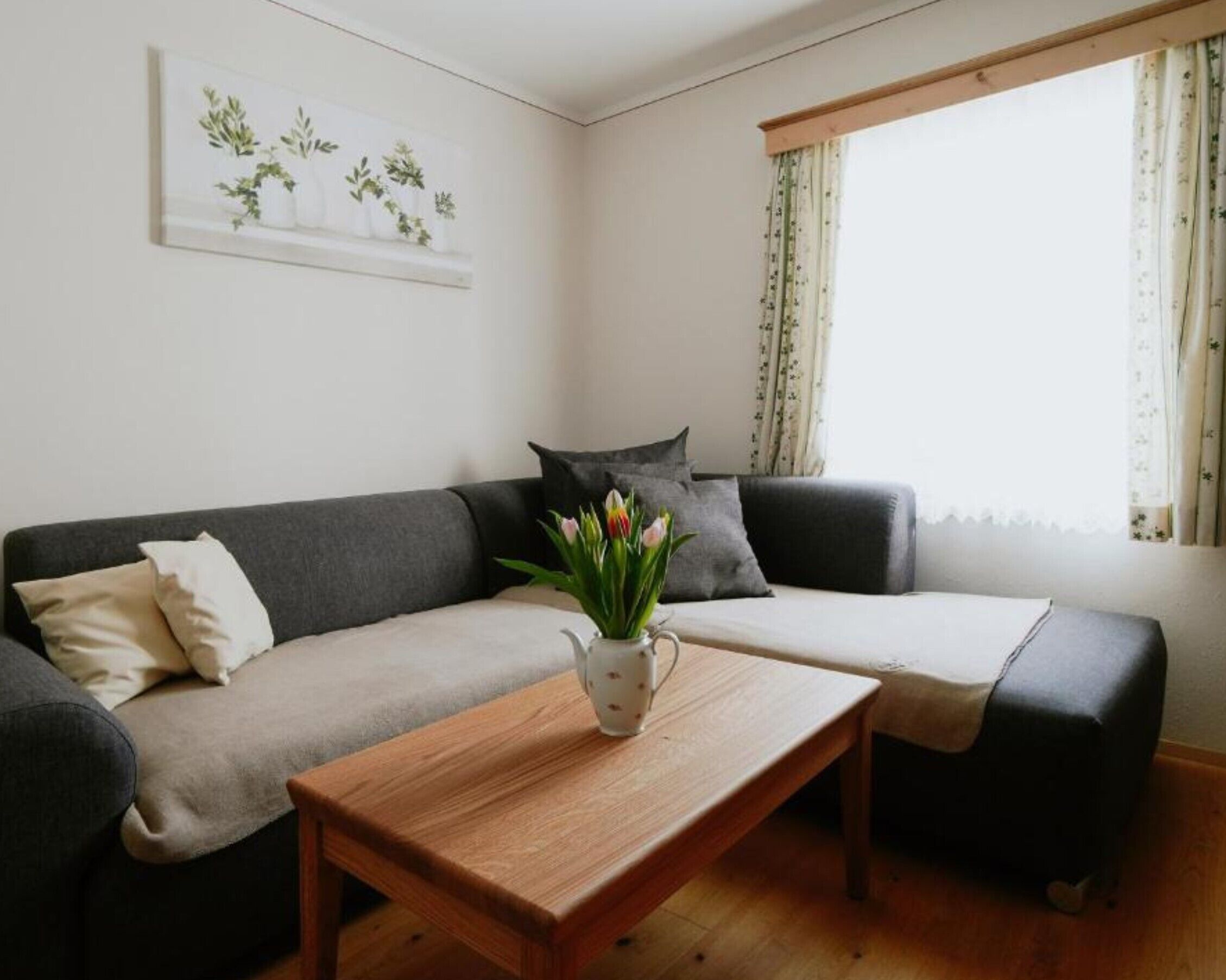 A living room with a sofa, a coffee table, and a window with curtains.